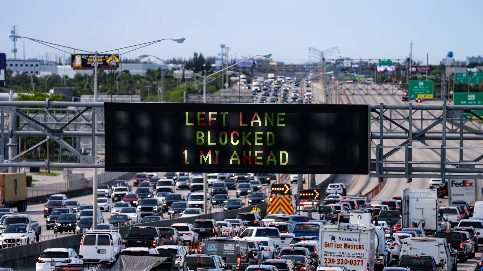 Congested highway traffic approaching downtown Miami with an overhead dynamic message sign