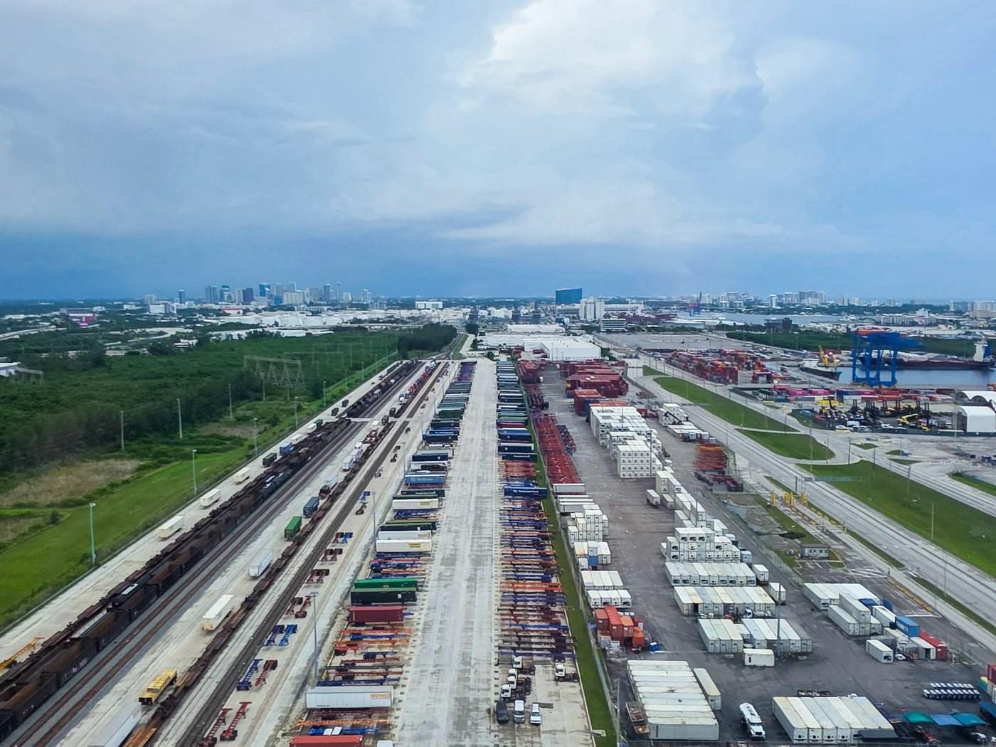 Aerial view of intermodal rail yard, freight facilities, and nearby port cranes