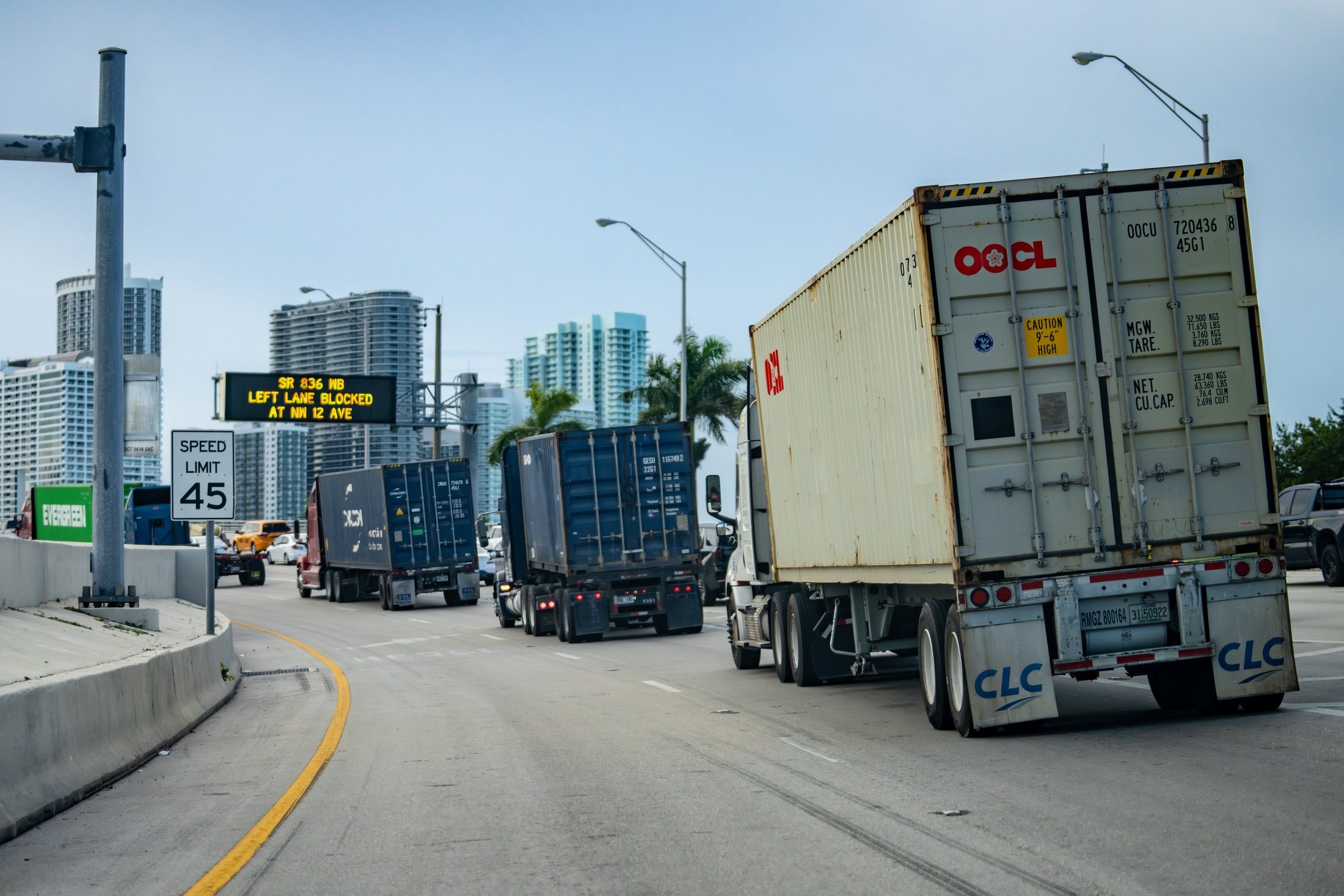 Container trucks traveling on a roadway near PortMiami and downtown Miami